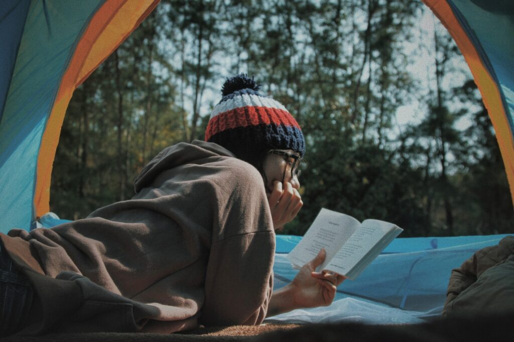 Frau liest Buch im Zelt